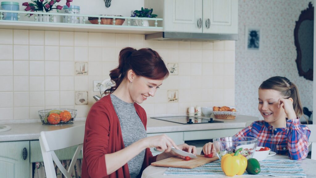 A mom and daughter prepare food in the kitchen.